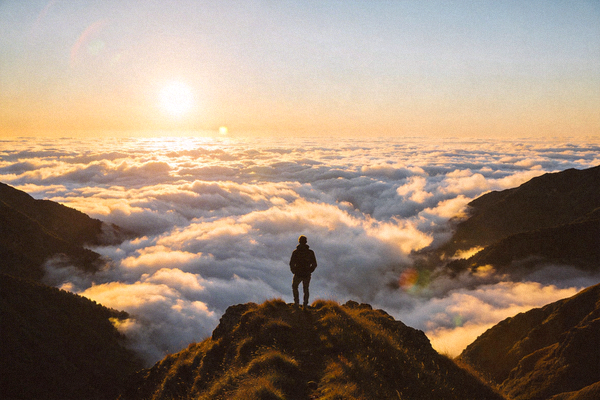 日出时分徒步者站在山脊上眺望远方的壮丽云海